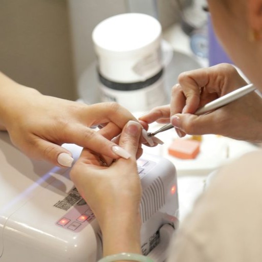 A nail technician carefully shapes a client's nails in a salon setting.